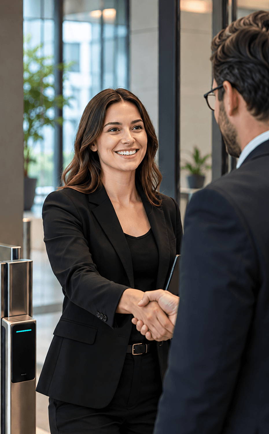 A ShieldPoint consultant shaking hands with a client beside an access-control turnstile in a modern office lobby